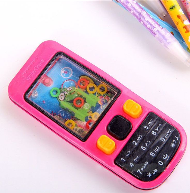 This may contain: a pink cell phone sitting on top of a table next to pencils and markers