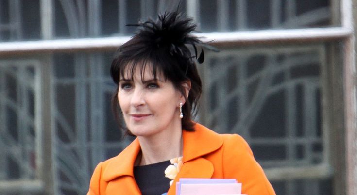 This may contain: a woman in an orange jacket carrying two books